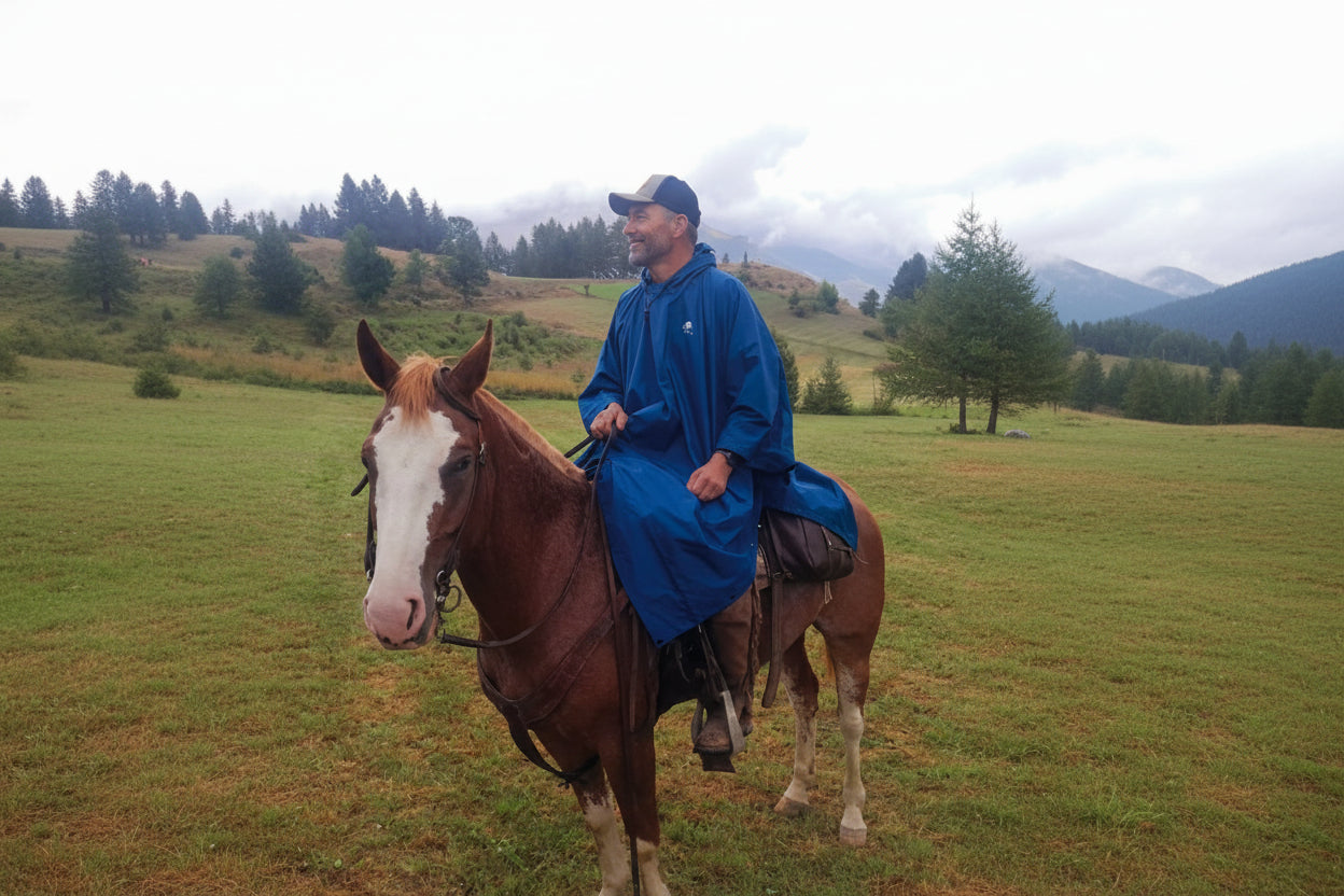 Uomo a cavallo in un paesaggio montano con indosso il Poncho Uragan-Tex mygesp
