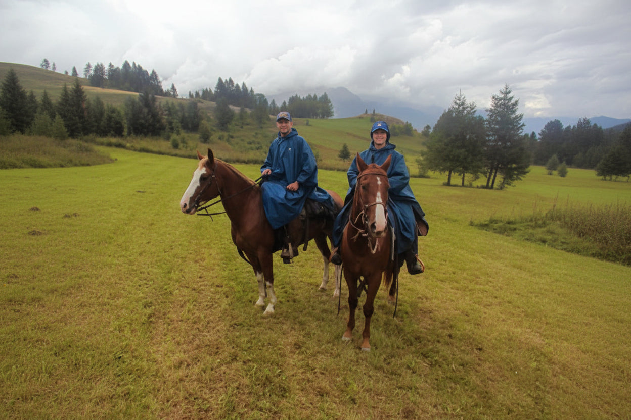 Uomo e donna a cavallo in un paesaggio montano con indosso il Poncho Uragan-Tex mygesp
